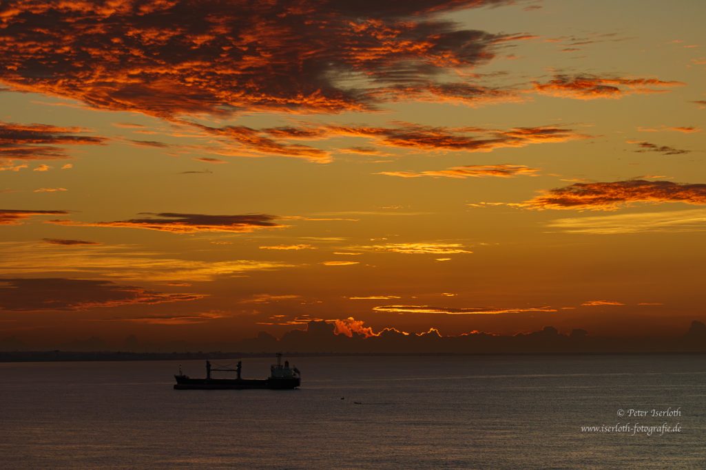 Fotografie von einem Sonnenaufgang mit auslaufendem Frachtschiff , Bucht von Santo Domingo, Dom-Rep.