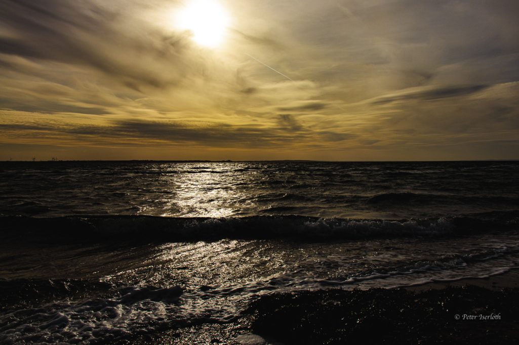 Fotografie vom Strand der Ostsee, zur See, bei untergehender Sonne, mit besonderer Lichtstimmung der Wolken.