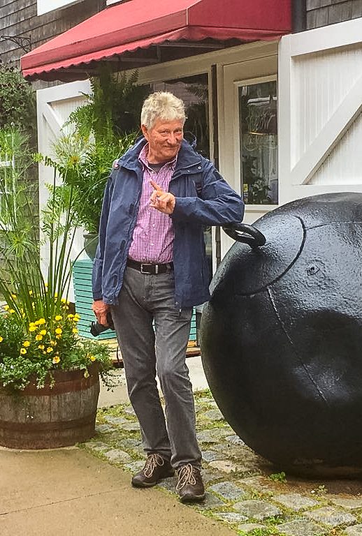 Ein Mann - Peter Iserloth -  in einem blauen Jackett steht neben einem großen schwarzen Objekt im Freien.