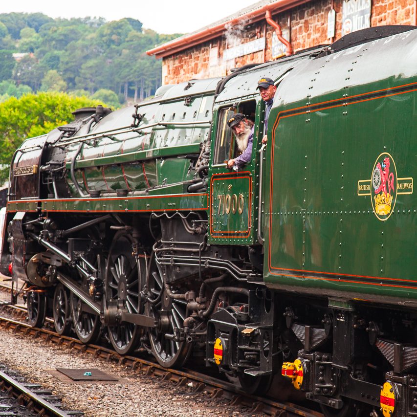 Dampflok mit grüner Lackierung, Fahrer schaut aus dem Fenster. Historische Eisenbahn.