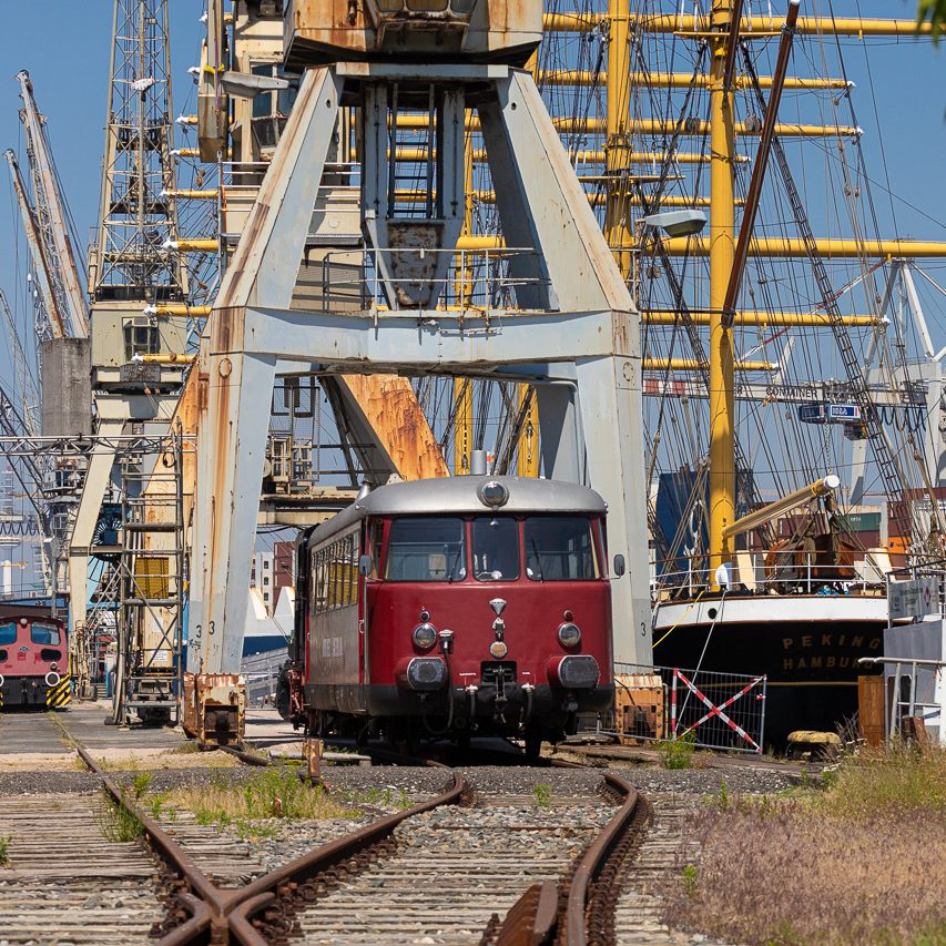 Rote Lokomotive auf Bahngleisen zwischen Kränen im Museums-Hafen Hamburg.