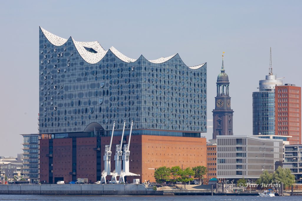 Fotografie der Hamburger Elbphilharmonie mit dem Michel im Hintergrund.