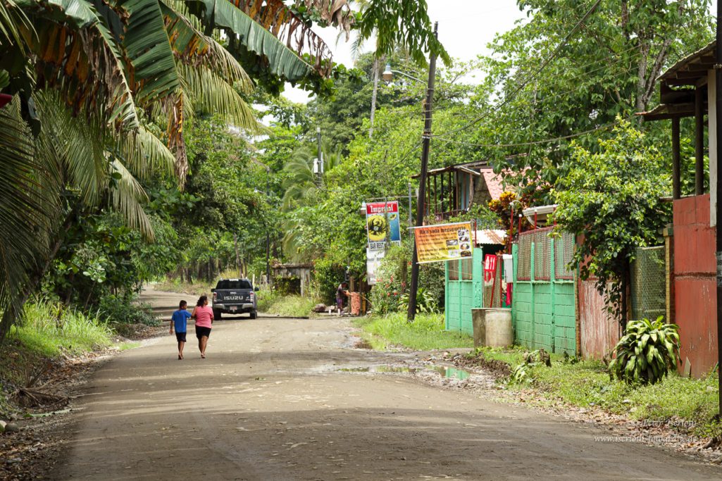 Fotografie der Hauptstraße in Rio Blanco, Costa Rica, mit Urwald und zwei Personen.