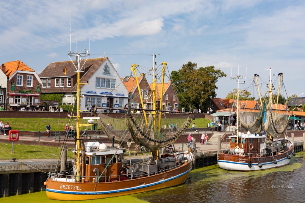 Fischereihafen mit traditionellem Boot und bunten Häusern im Hintergrund.